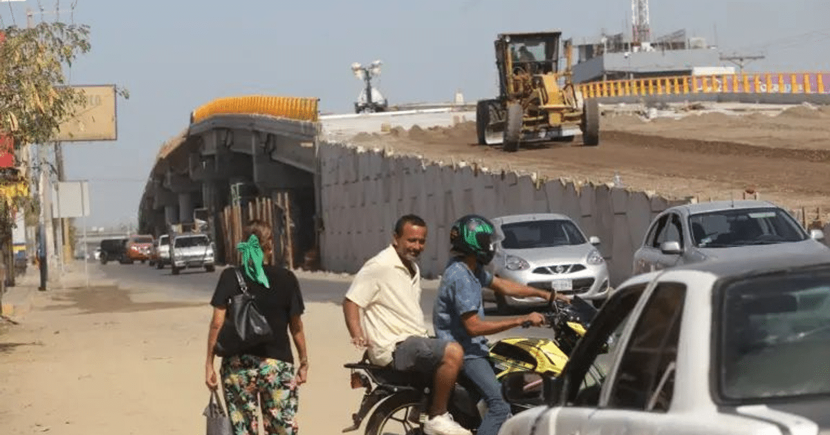 Personas caminando en una calle urbana con construcción de puente al fondo