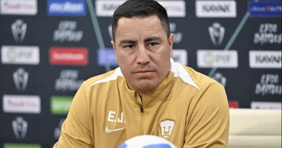 Hombre con chaqueta amarilla en conferencia de prensa sobre Pumas vs Alajuelense