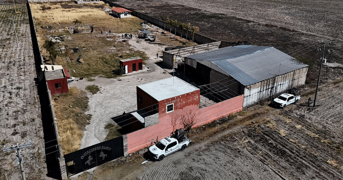 Vista aérea de un rancho en Teuchitlán con edificios rojos y techos de metal, vehículos y postes de electricidad.