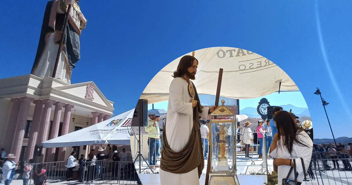 Evento al aire libre en Badiraguato con estatua religiosa y altar de Jesús, rodeado de personas y carpas gubernamentales.