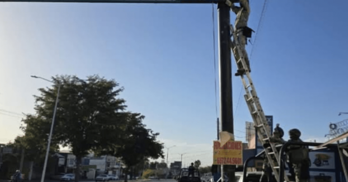 Operativo de seguridad en Culiacán con personas trabajando en un poste de luz y observadores en un vehículo.