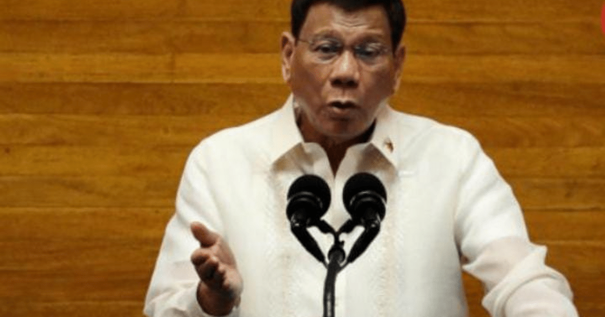 Persona hablando en un entorno formal con micrófono y fondo de madera, posiblemente relacionado con el arresto de Duterte.