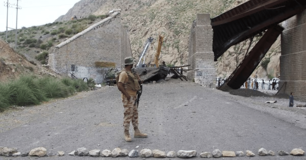 Militar en zona afectada con puente dañado y grúa en Baluchistán