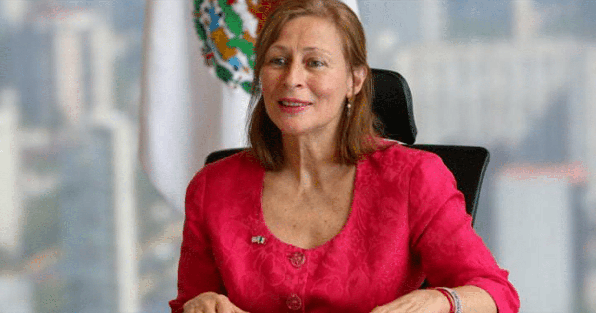 Mujer sonriente con blusa rosa en oficina, relacionada con el nombramiento de Tatiana Clouthier en el Instituto de Mexicanas y Mexicanos en el Exterior.