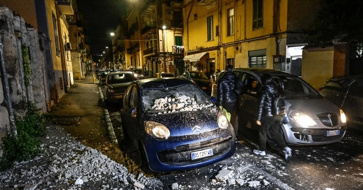 Calle nocturna en Pozzuoli con vehículos y escombros tras el terremoto en Campos Flégreos.