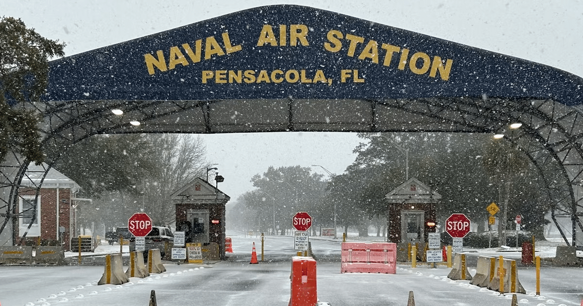 Entrada nevada de la Estación Aérea Naval de Pensacola con arco y señales de tráfico