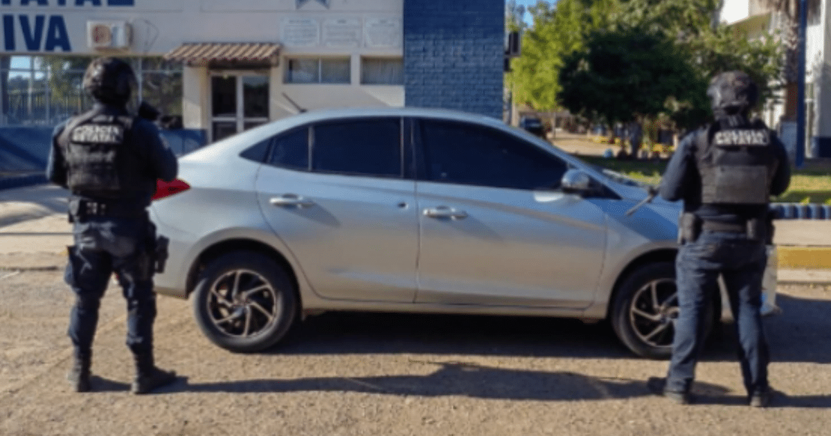 Agentes de seguridad armados frente a un automóvil plateado en un operativo de vigilancia.