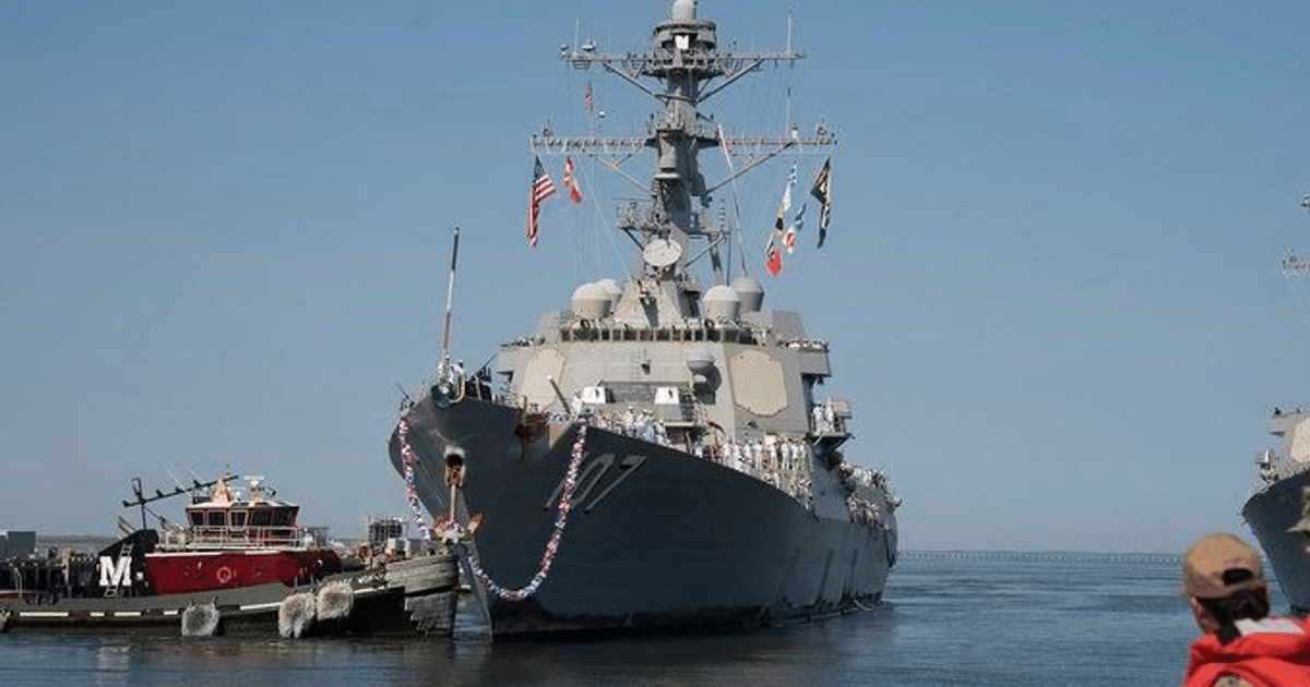 Buque destructor USS Gravely decorado en el muelle, con banderas y personas a bordo, en un día soleado.