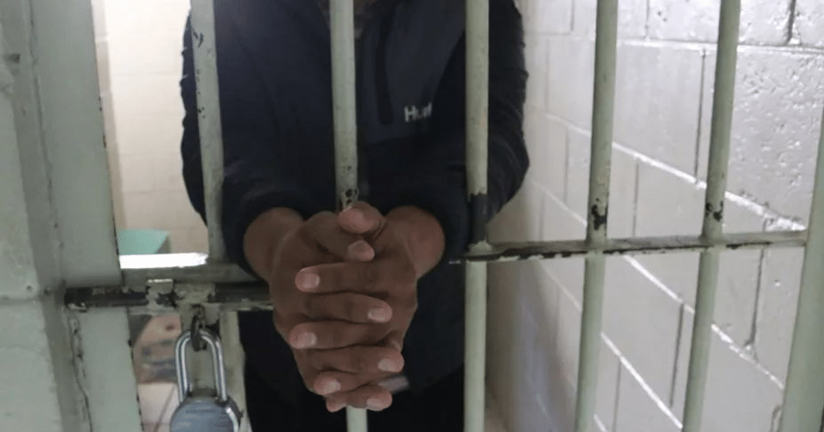 Manos sujetando barras de celda con candado visible, simbolizando condena judicial en Culiacán.