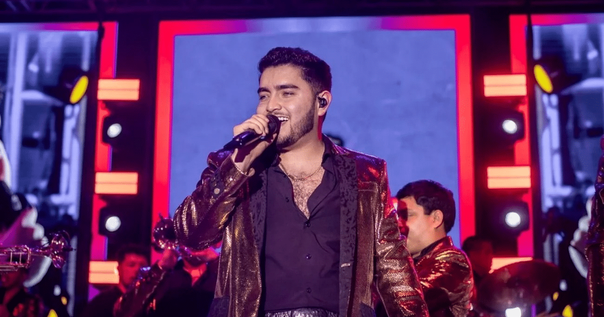Cantante en el escenario del Carnaval de Tenosique con chaqueta brillante y micrófono.