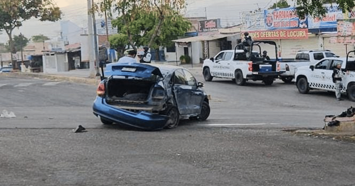 Automóvil azul dañado tras accidente en Culiacán, con patrullas y edificios al fondo.