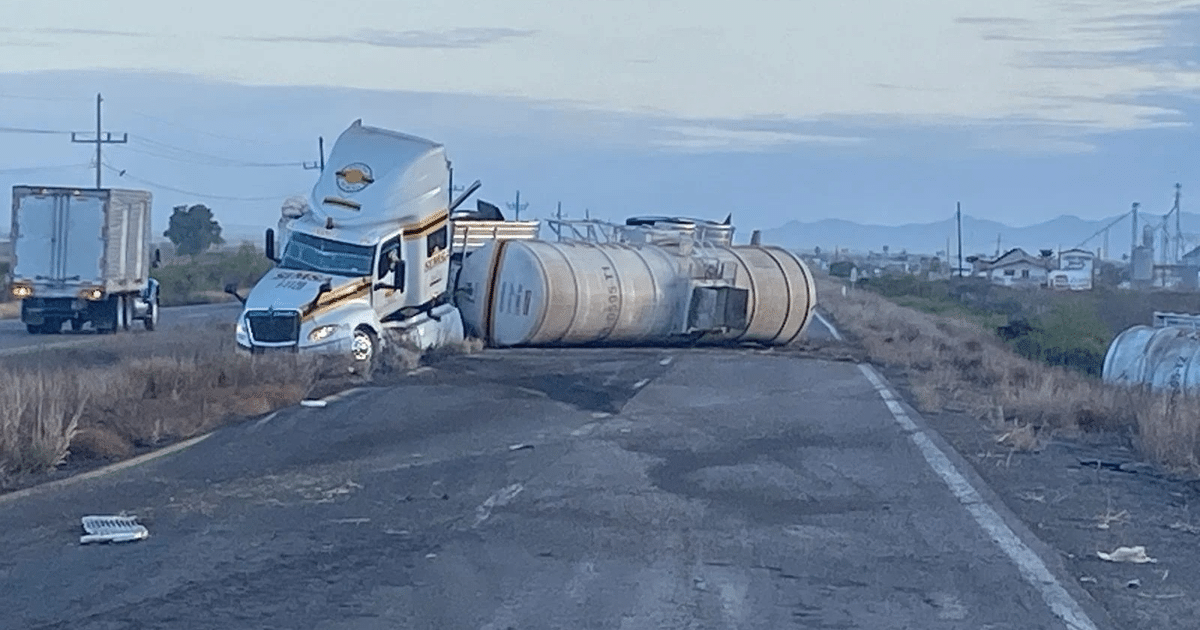 Camión cisterna volcado en la carretera México 15, con otro camión en movimiento al fondo y vegetación alrededor.