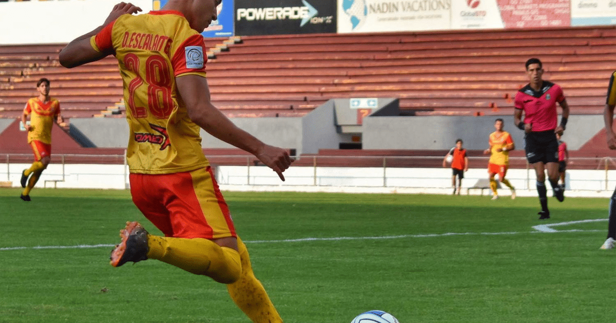 Jugador Escalante con el número 28 en acción durante un partido de fútbol, con un árbitro y otros jugadores en el fondo.