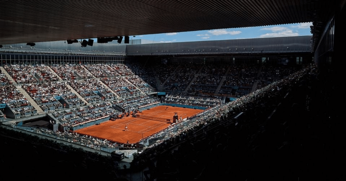 Partido de tenis en La Caja Mágica con jugadores en acción y espectadores en las gradas