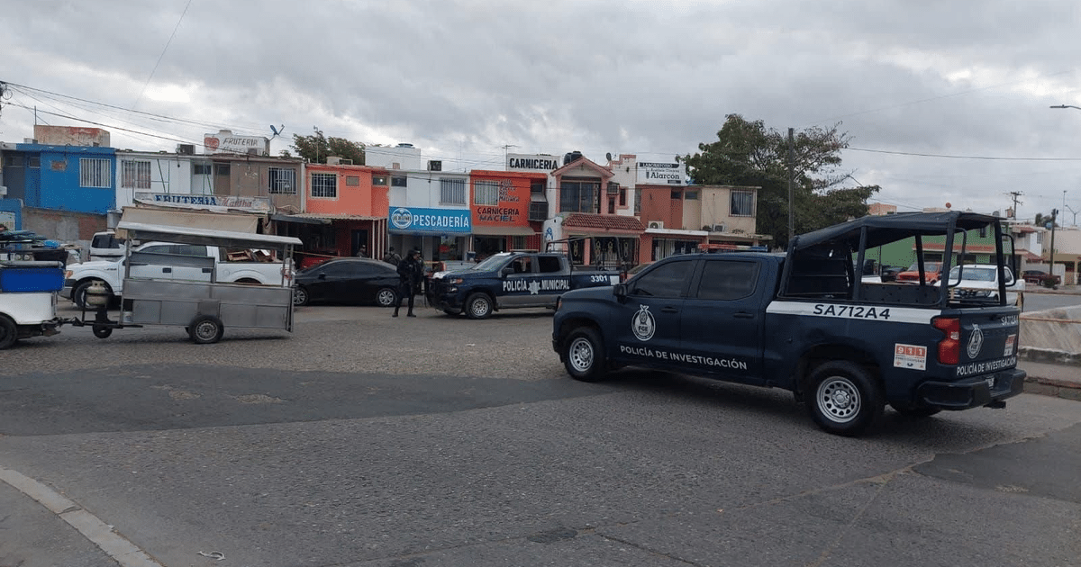 Calle comercial en Mazatlán con vehículos policiales y tiendas bajo un cielo nublado.