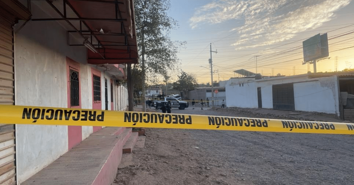 Cinta de precaución amarilla en calle de Culiacán con vehículos policiales al atardecer.