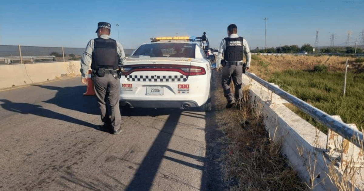 Oficiales de policía junto a un vehículo con luces intermitentes en una carretera, relacionados con un caso de homicidio en Culiacán.