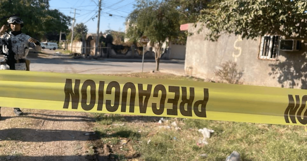 Cinta de precaución amarilla en escena de crimen en Culiacán con oficial de seguridad y edificios de fondo.