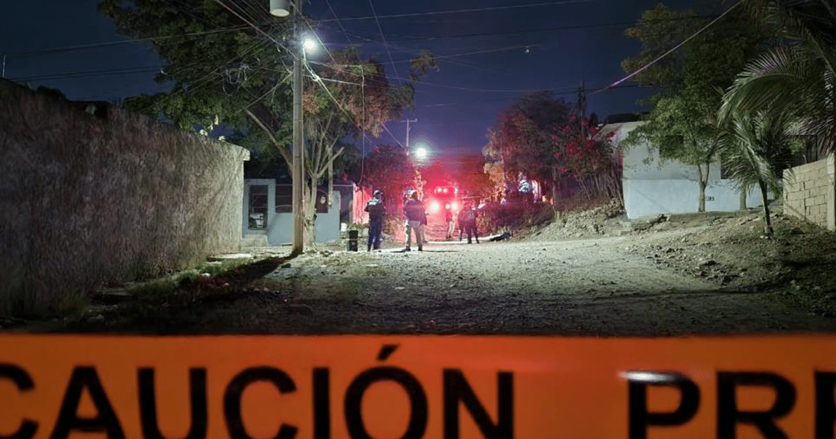 Calle nocturna en Culiacán con letrero de advertencia y luces de emergencia