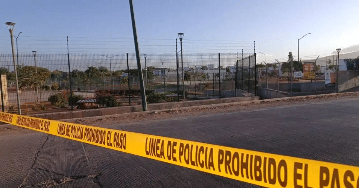 Línea de policía amarilla en escena de crimen en Culiacán, Sinaloa, con estructuras y vegetación al fondo.