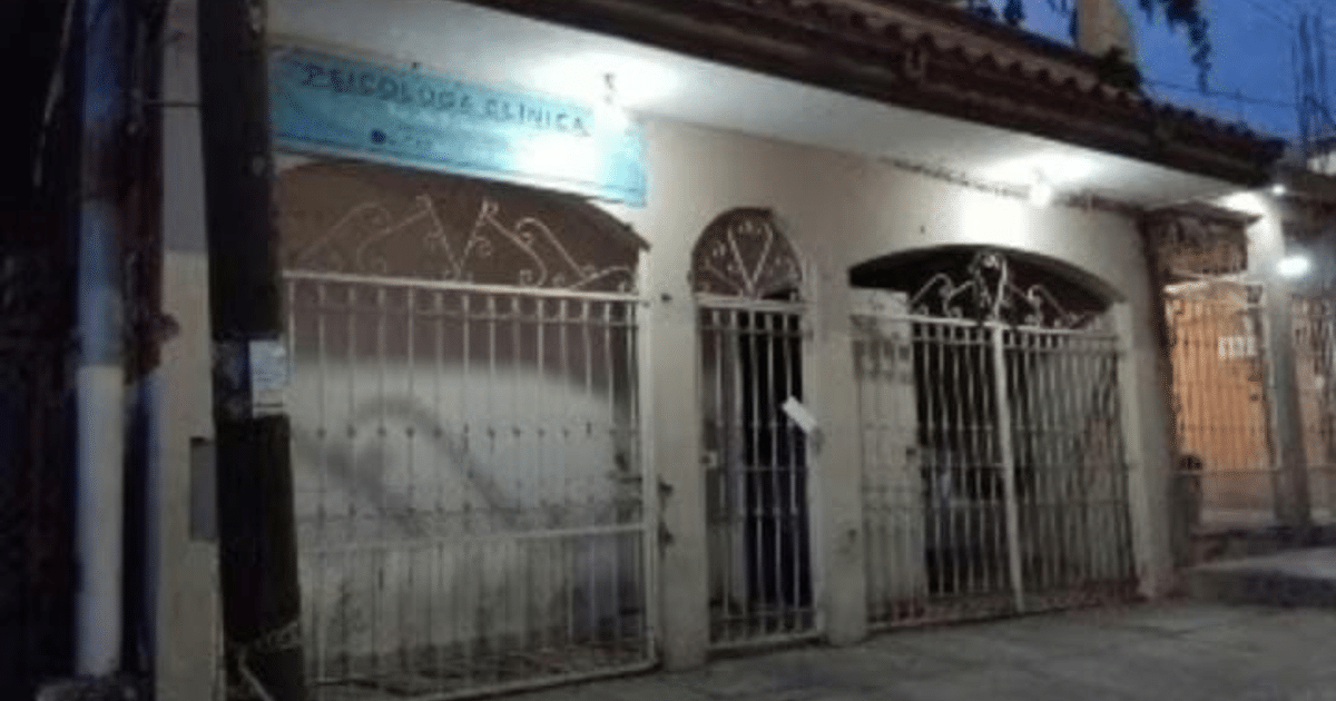 Fachada de clínica psicológica con letrero y rejas metálicas en ambiente nocturno