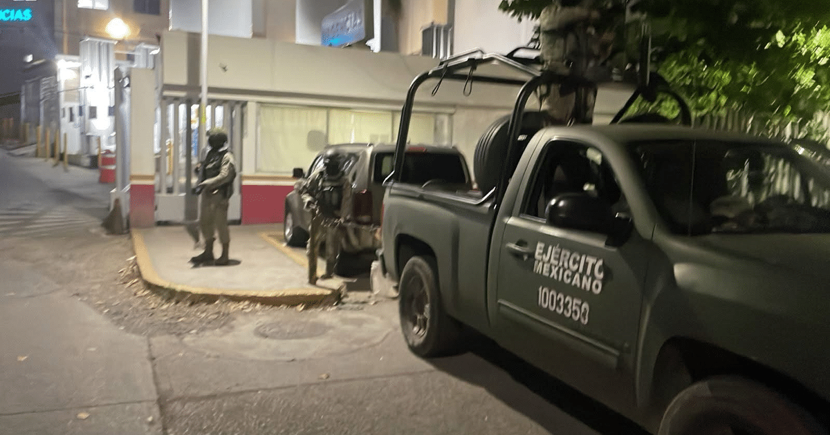 Vehículo del Ejército Mexicano estacionado en zona urbana nocturna con soldado vigilando.