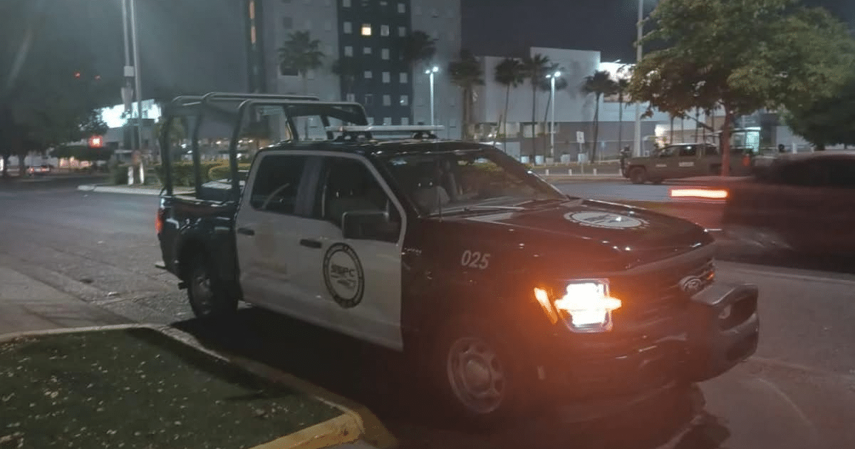 Camioneta de policía estacionada en Culiacán durante la noche, con edificios y luces al fondo.