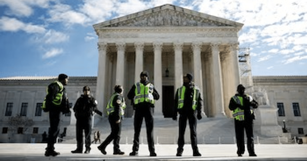Agentes de seguridad con chalecos reflectantes frente a un tribunal con columnas en un día claro.
