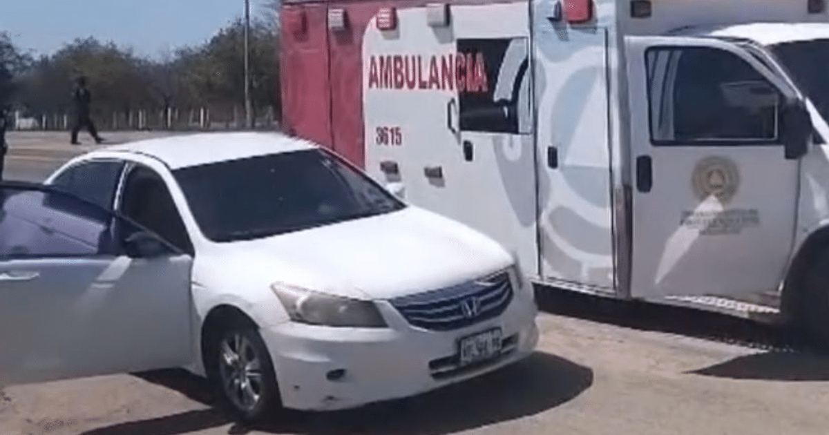 Sedán blanco con puerta abierta y ambulancia al fondo en escena de enfrentamiento armado en Mazatlán.