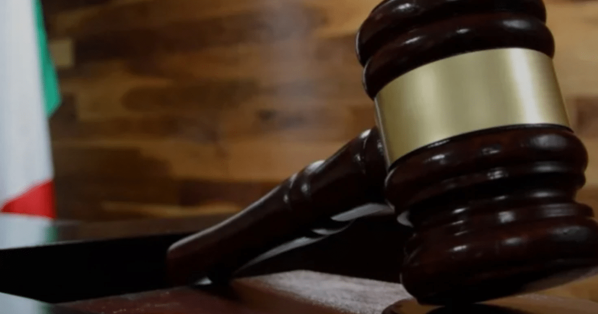 Martillo de juez sobre fondo de madera con bandera de México, simbolizando justicia y legalidad.