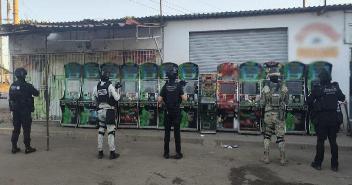 Oficiales de seguridad observan máquinas tragamonedas durante un operativo en Sinaloa.