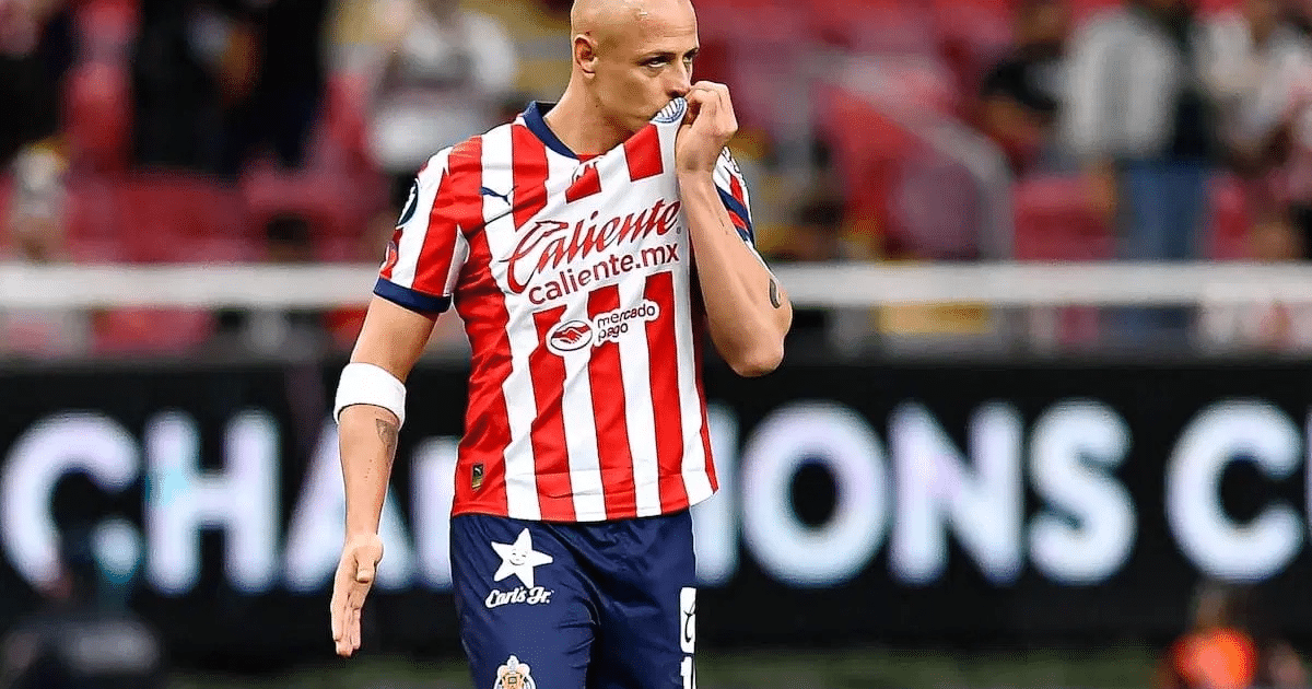 Jugador de fútbol besando su camiseta en un estadio lleno durante un partido.