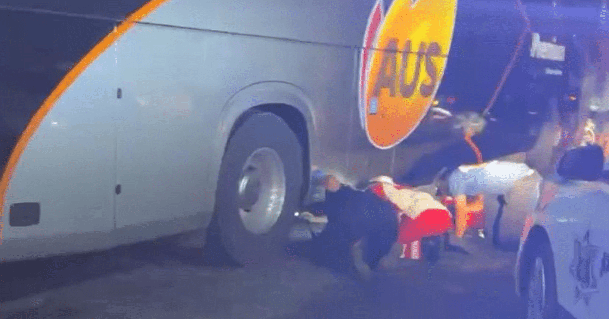 Personas revisando neumático de autobús gris con detalles naranjas tras accidente en Mazatlán.