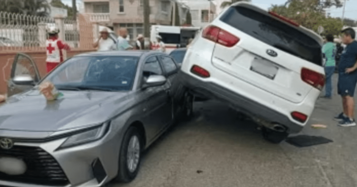 Accidente automovilístico en Puerto de Mazatlán con un coche blanco sobre uno gris, rodeado de personas y servicios de emergencia.