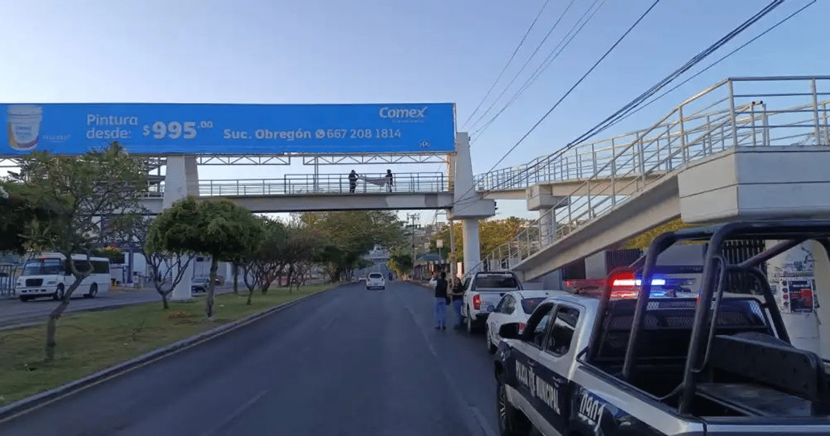 Calle en Culiacán con vehículos, anuncio de pintura, puente peatonal y presencia policial.