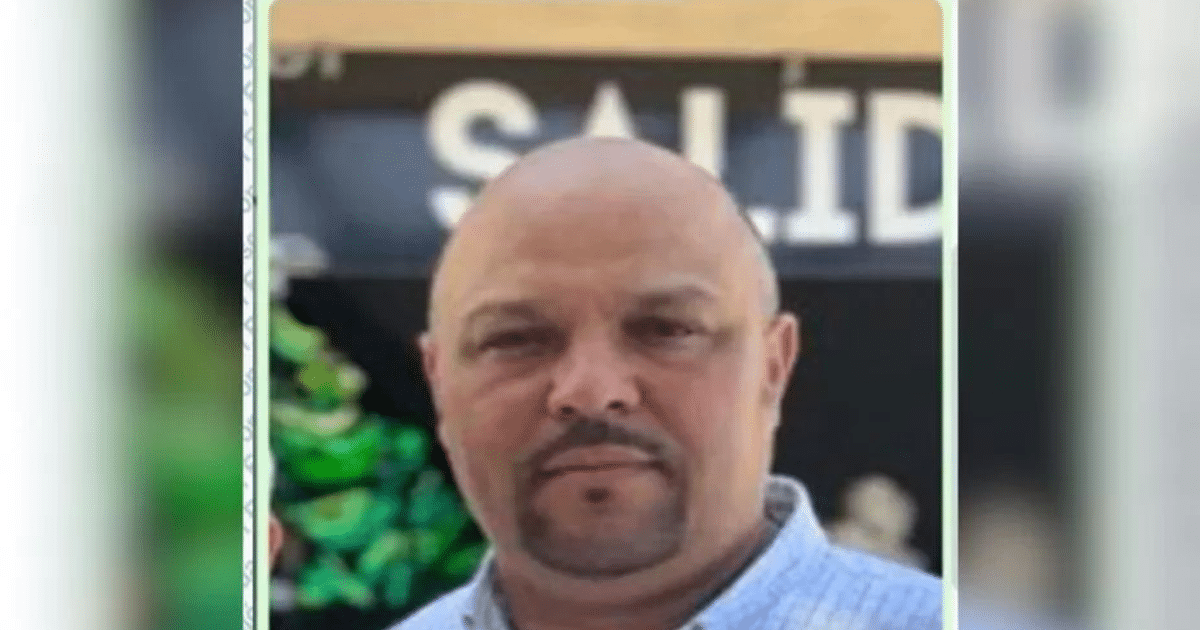 Hombre con camiseta clara frente a un letrero de 'SALID', relacionado con la desaparición de Hernán Herrera Espino.