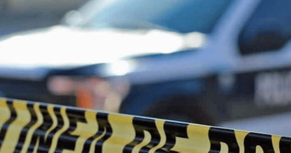 Cinta de advertencia amarilla y negra en carretera México 15 con coche de policía al fondo