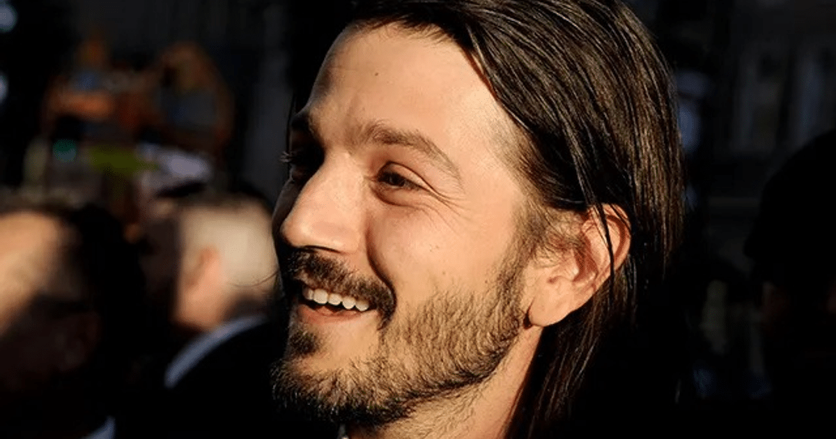 Hombre sonriente con cabello largo y barba en un entorno iluminado, simbolizando la influencia de Diego Luna en el cine.