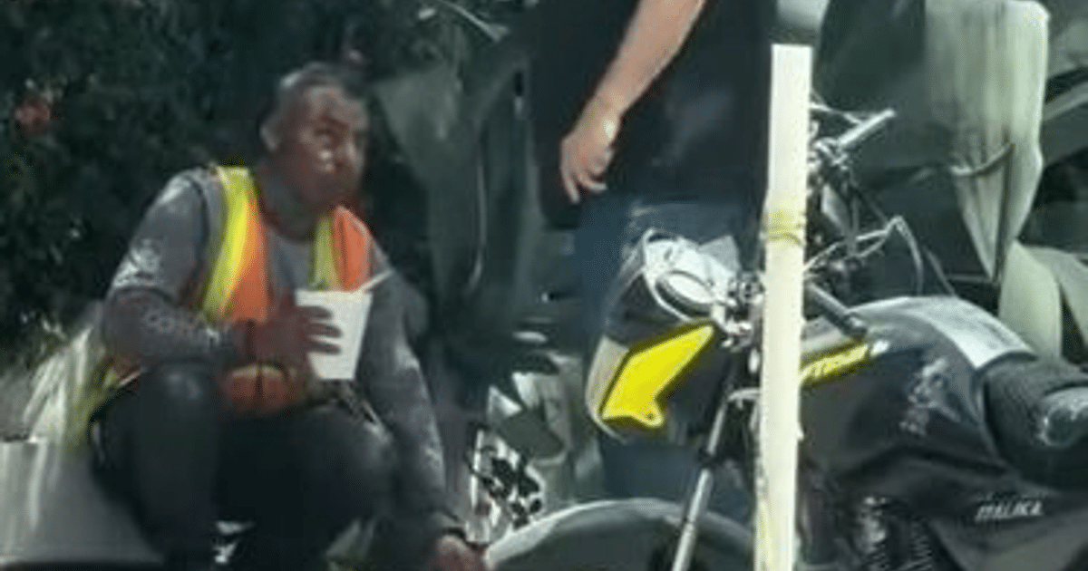 Trabajador de construcción con chaleco de seguridad sentado junto a motocicleta en Mazatlán, relacionado con incidente de discriminación.