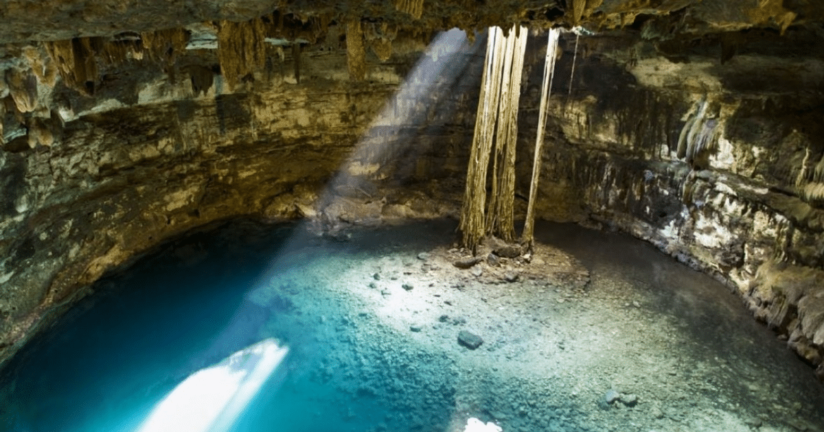 Cenote en Yucatán con agua clara, formaciones rocosas y rayos de luz