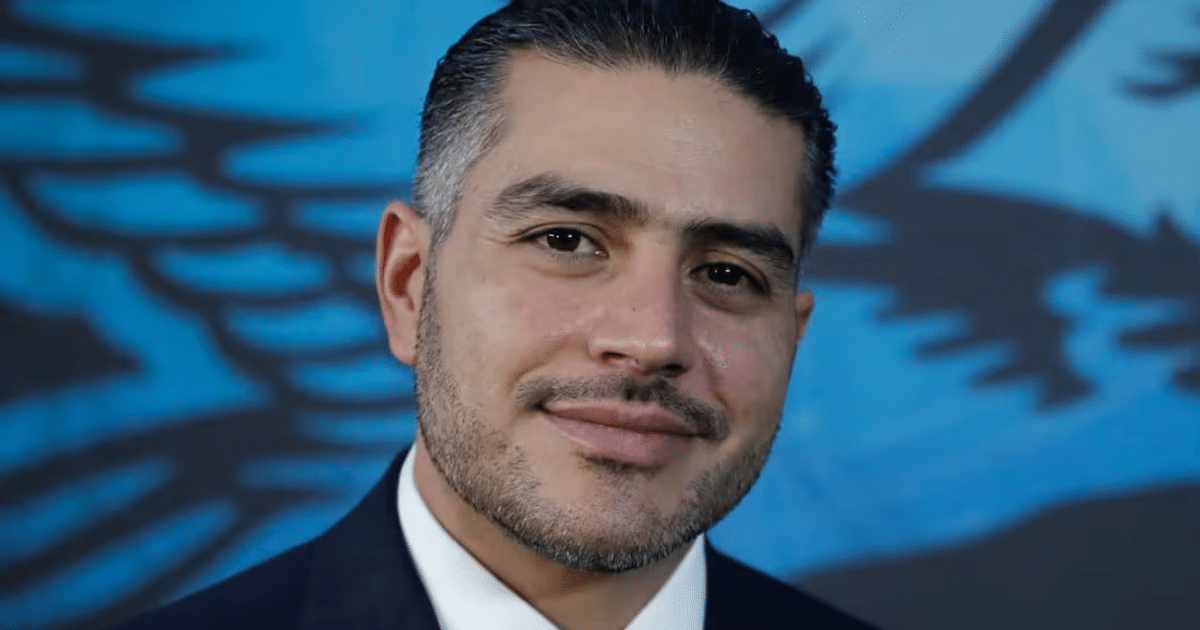 Hombre en traje sonriendo con fondo azul, vinculado a la Estrategia Nacional de Seguridad Pública 2025.