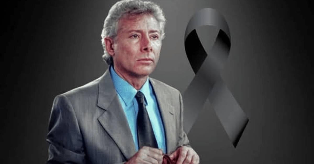 Hombre en traje gris con lazo negro, simbolizando luto por Arsenio Campos.