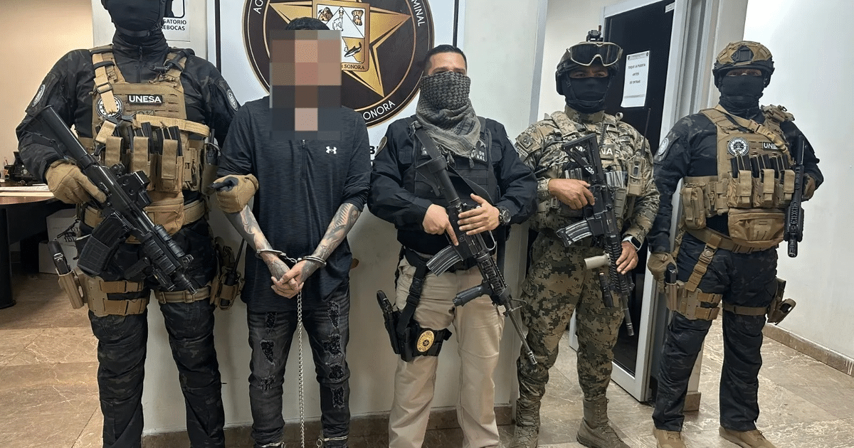 Hombres en uniformes tácticos detienen a Oswaldo Nathanahee en una estación de policía.