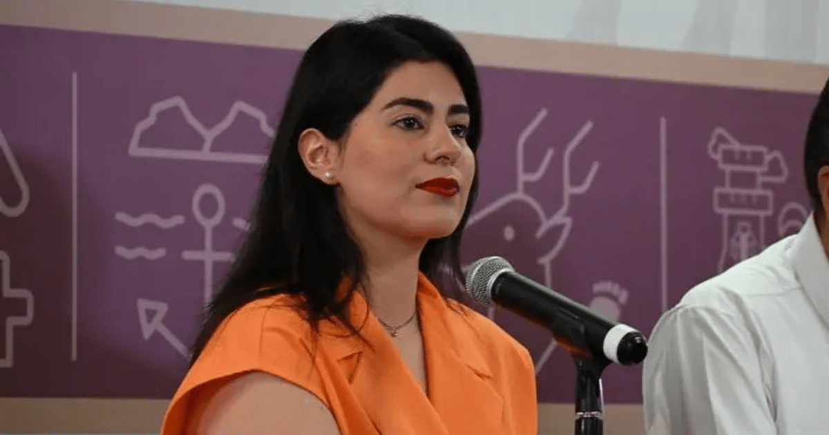 Mujer hablando en un evento sobre violencia de género en Sinaloa, con un micrófono frente a ella y un fondo ilustrado.