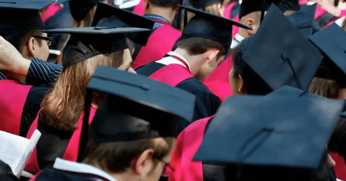 Estudiantes en ceremonia de graduación con togas y birretes negros, algunos con cintas rojas, en un contexto de debate sobre políticas universitarias.
