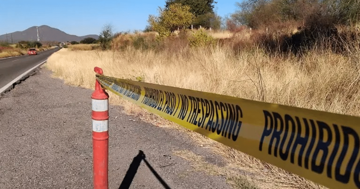 Carretera en Sinaloa con cinta de advertencia y vehículo rojo estacionado