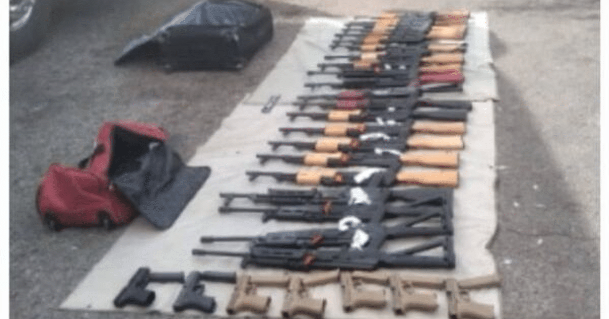 Arsenal de armas incautadas en operativo en caseta de peaje, incluyendo fusiles y pistolas organizados en líneas.