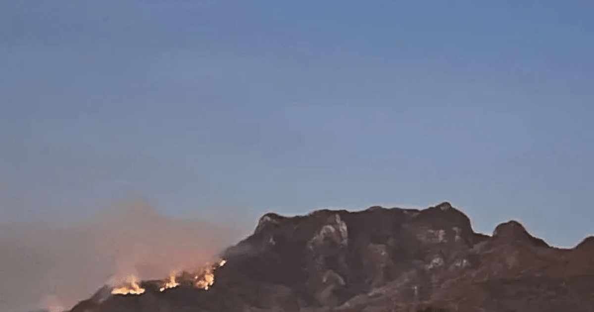 Paisaje montañoso con incendio forestal en el cerro Yauco, llamas y humo visibles.