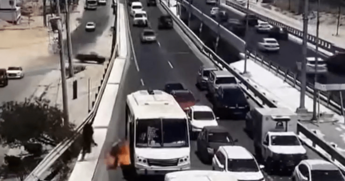 Autobús blanco en llamas en carretera de Cabo San Lucas, captado por cámara de seguridad.