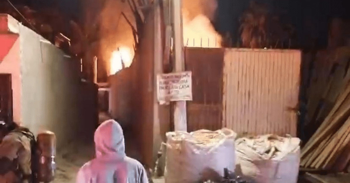 Callejón nocturno en Mazatlán con incendio al fondo y persona de espaldas